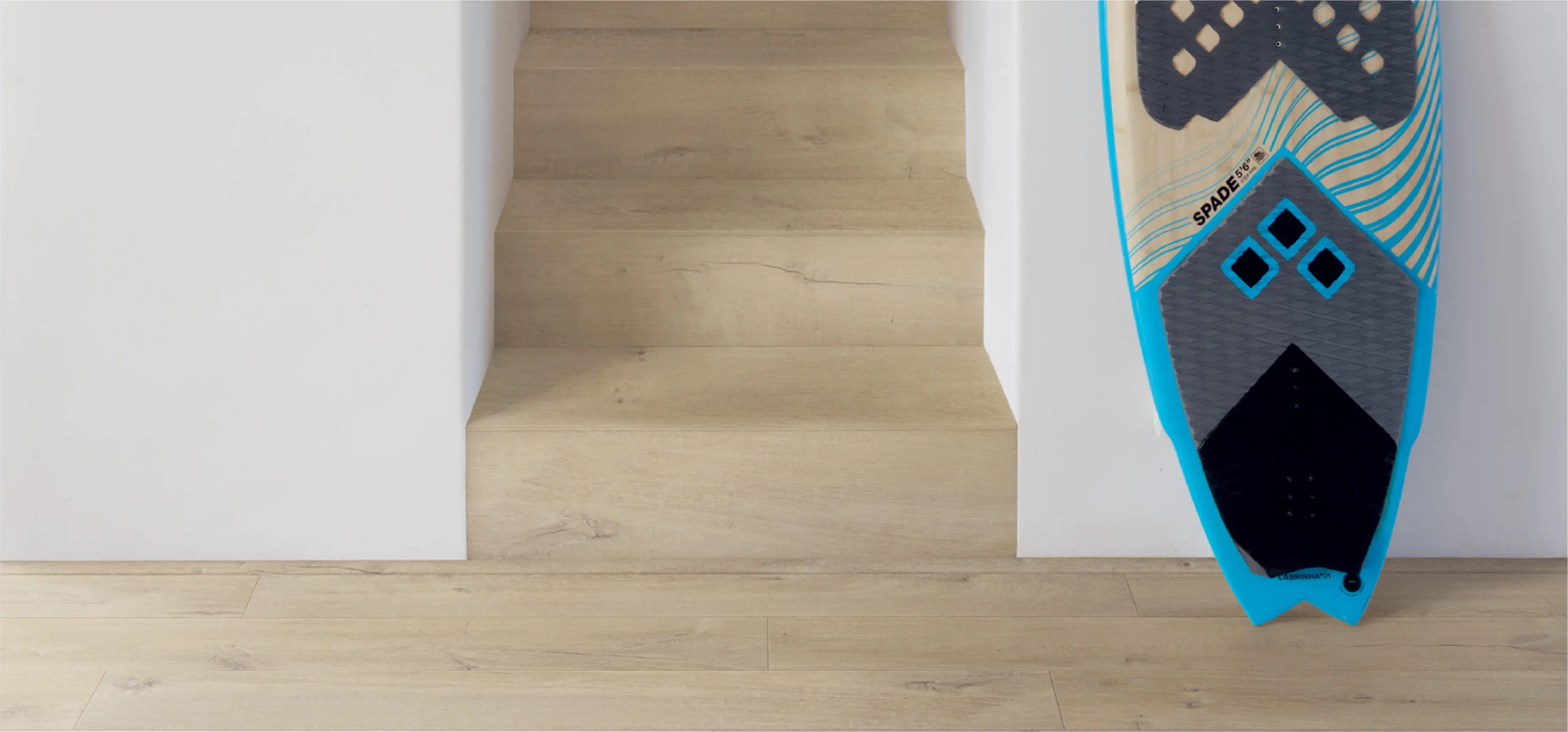 明るい木目調のフローリングと階段が特徴のシンプルな室内空間